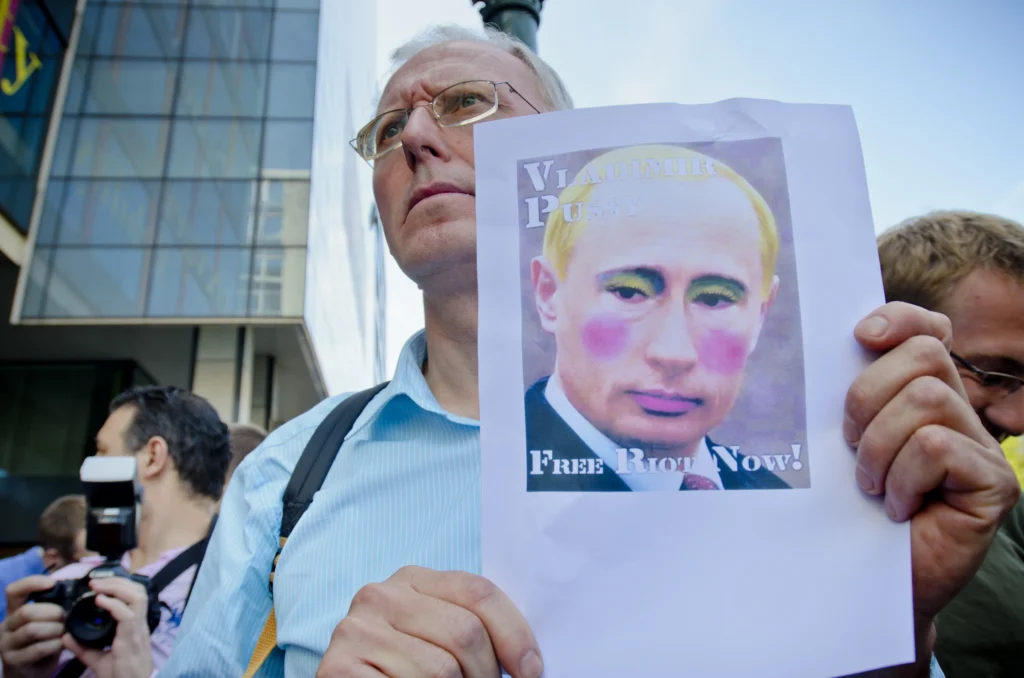 A protester holding a portrait of Vladimir Putin in drag make-up reading “Free Pussy Riot Now!” at a solidarity rally in August 2012